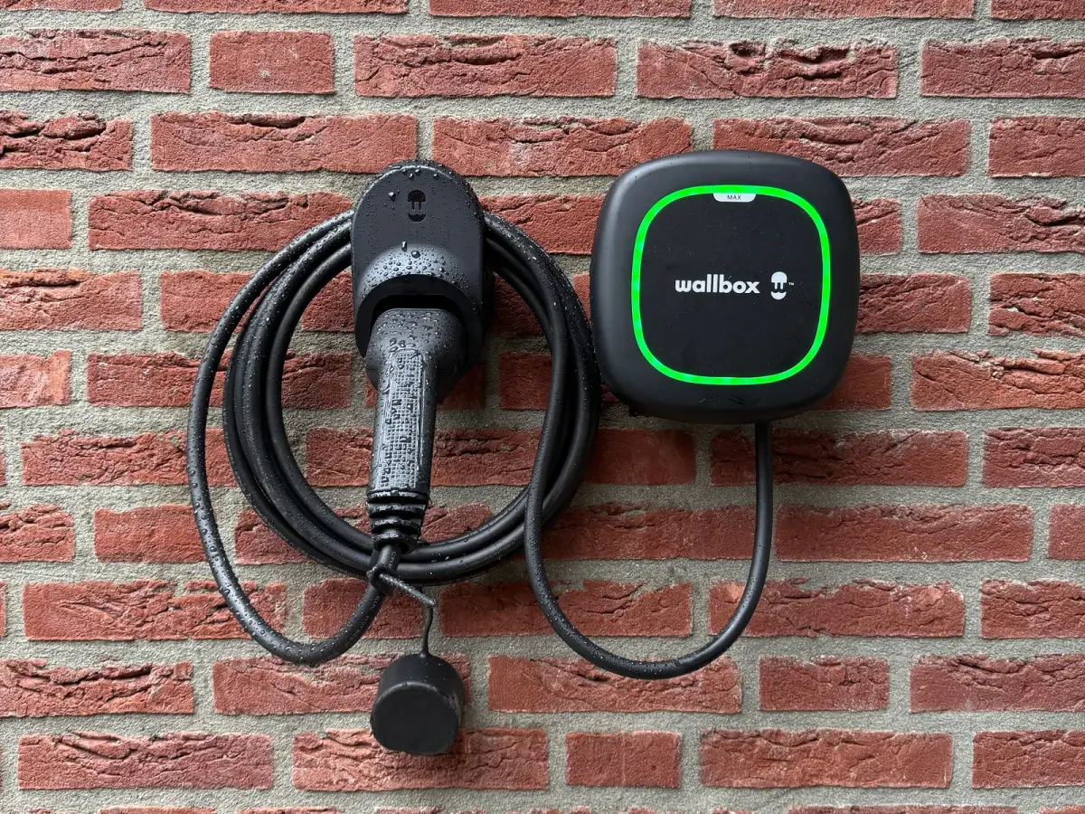 Laadpunt met laadkabel aan een bakstenen gevel