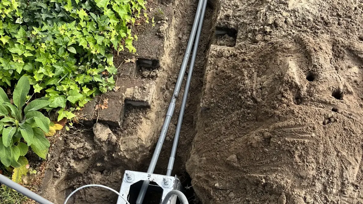 Sleuf in de tuin met de grondkabel en een aansluitdoos